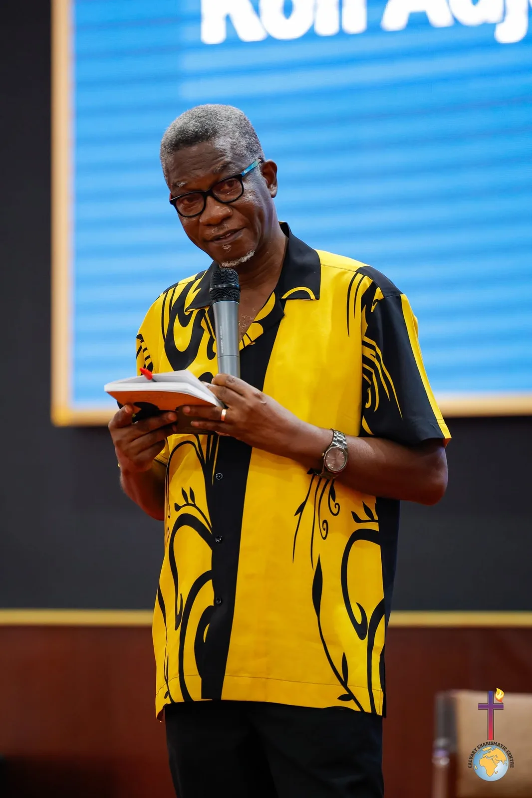 Rev. Vincent Acquaah reading from a book on stage
