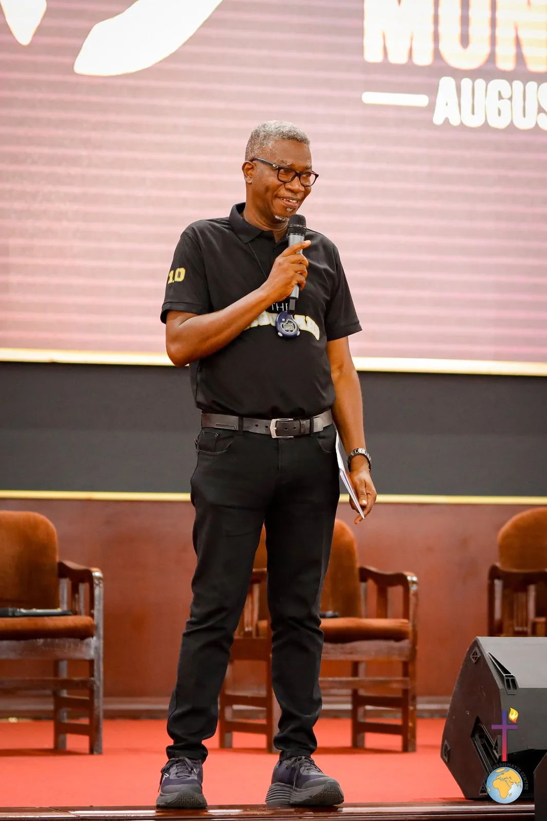 Rev. Vincent Acquaah standing on stage, smiling as he speaks