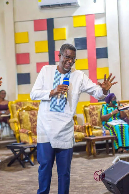 Rev. Vincent Acquaah speaking with a microphone in a meeting room