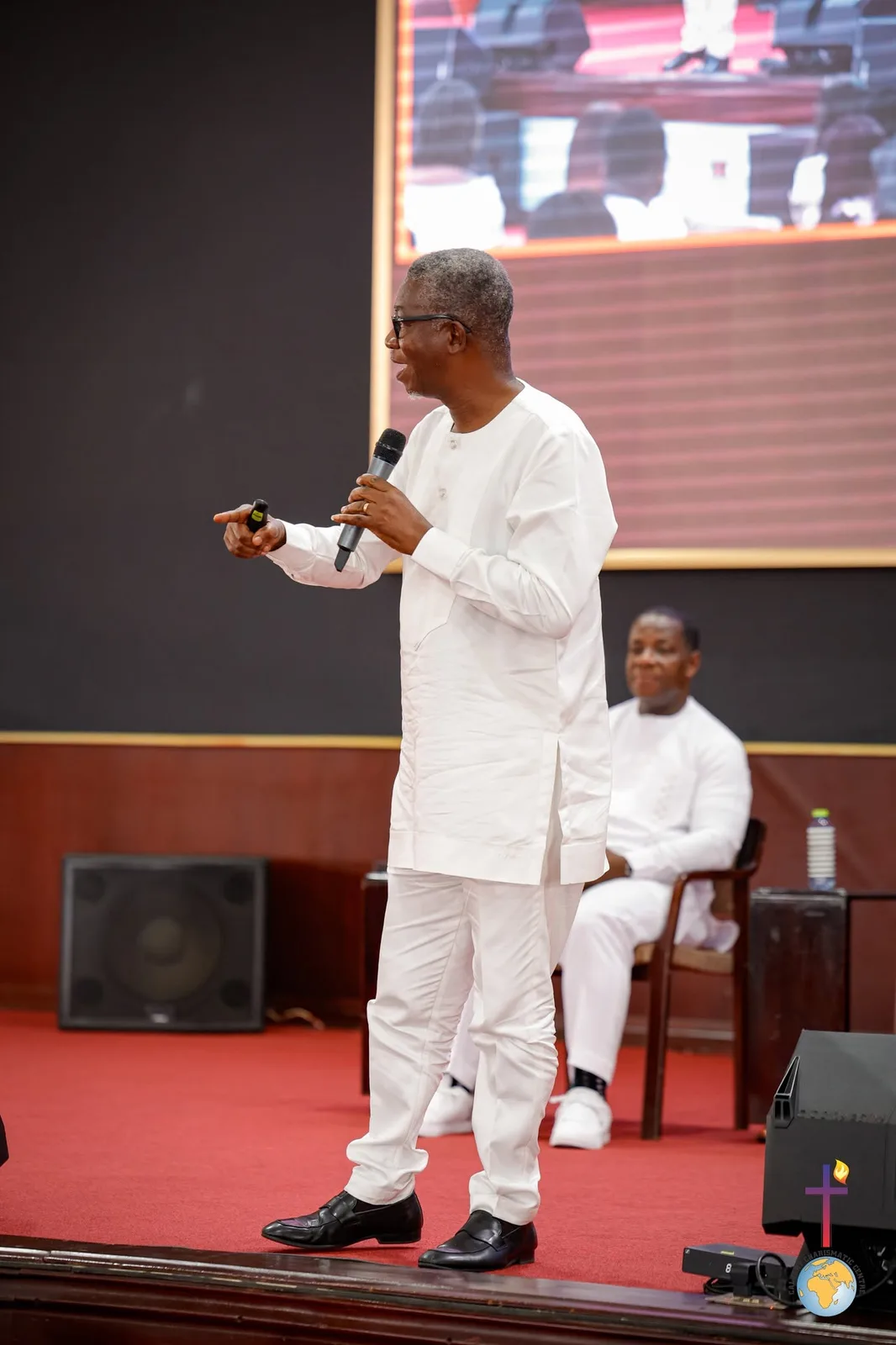 Rev. Vincent Acquaah speaking on stage in white