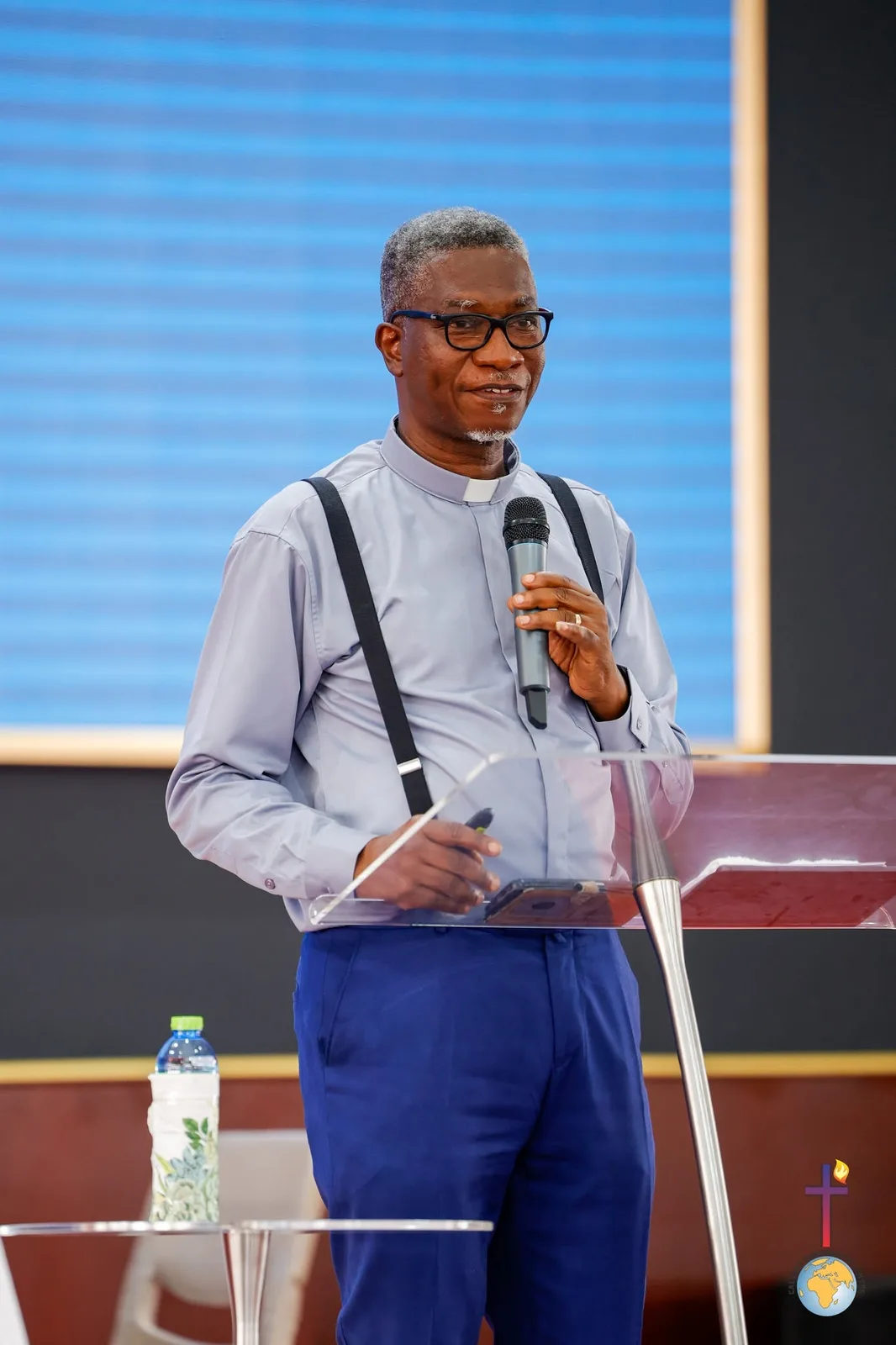 Rev. Vincent Acquaah smiling at a podium with a microphone